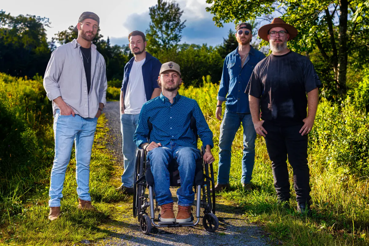 Connor Hirtle seated with the four other members of HIRTLE outdoors