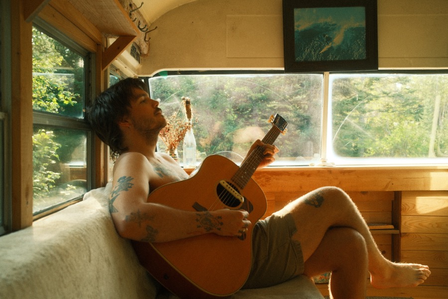 Braden Lam sitting on a bus in the sunshine, a self-portrait.
